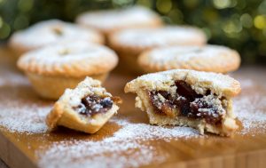 Mince pies photographed with filling exposed and dusted with icing sugar.